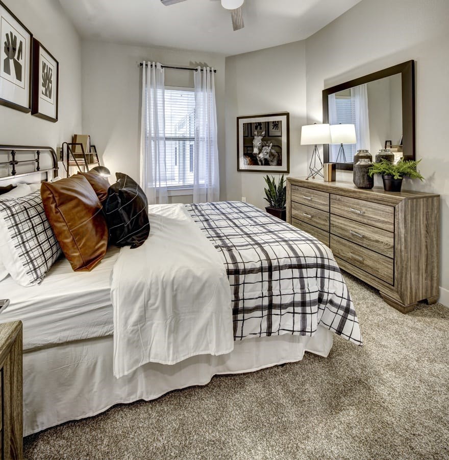 A bedroom with a bed, dresser, and mirror at Arise Riverside Apartments, Texas