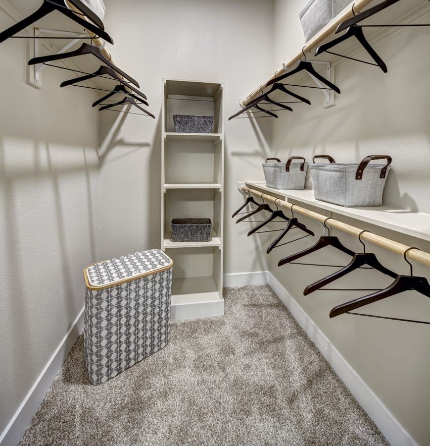 A white closet with a trash can and hangers at Arise Riverside Apartments, Austin, Texas