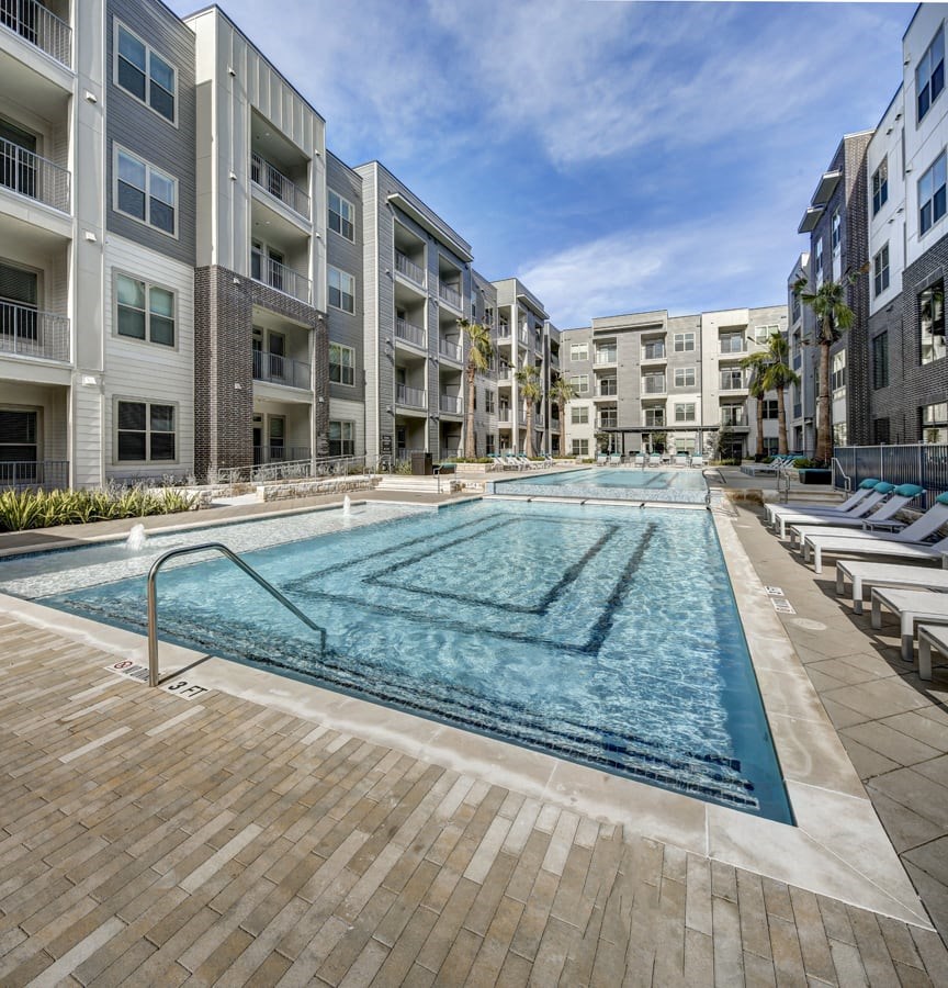 A large swimming pool in the middle of a courtyard surrounded by apartment buildings at Arise Riverside Apartments, Austin, TX