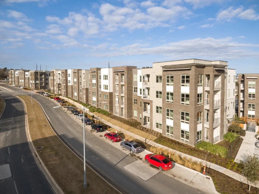 A row of apartment buildings with cars parked in front at Arise Riverside Apartments, Austin, Texas