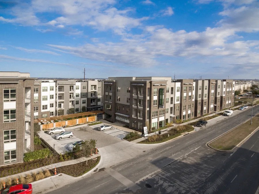 A row of apartment buildings with a parking lot in front at Arise Riverside Apartments, Austin, 78741
