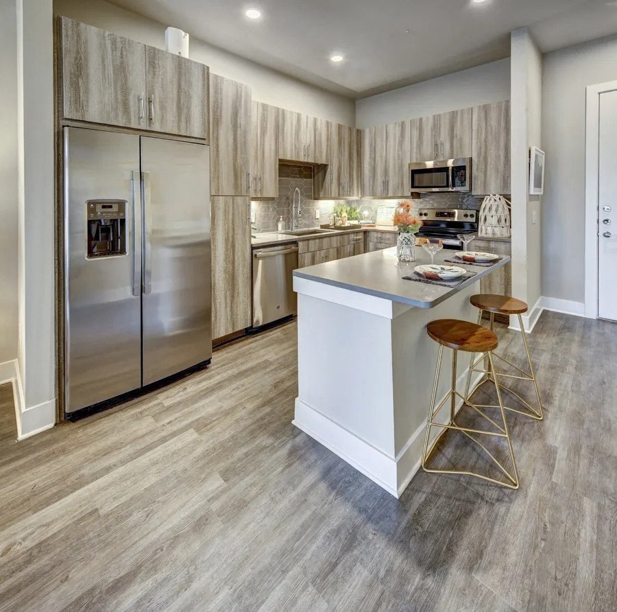 A modern kitchen with a white island and stainless steel appliances at Arise Riverside Apartments, Texas 78741