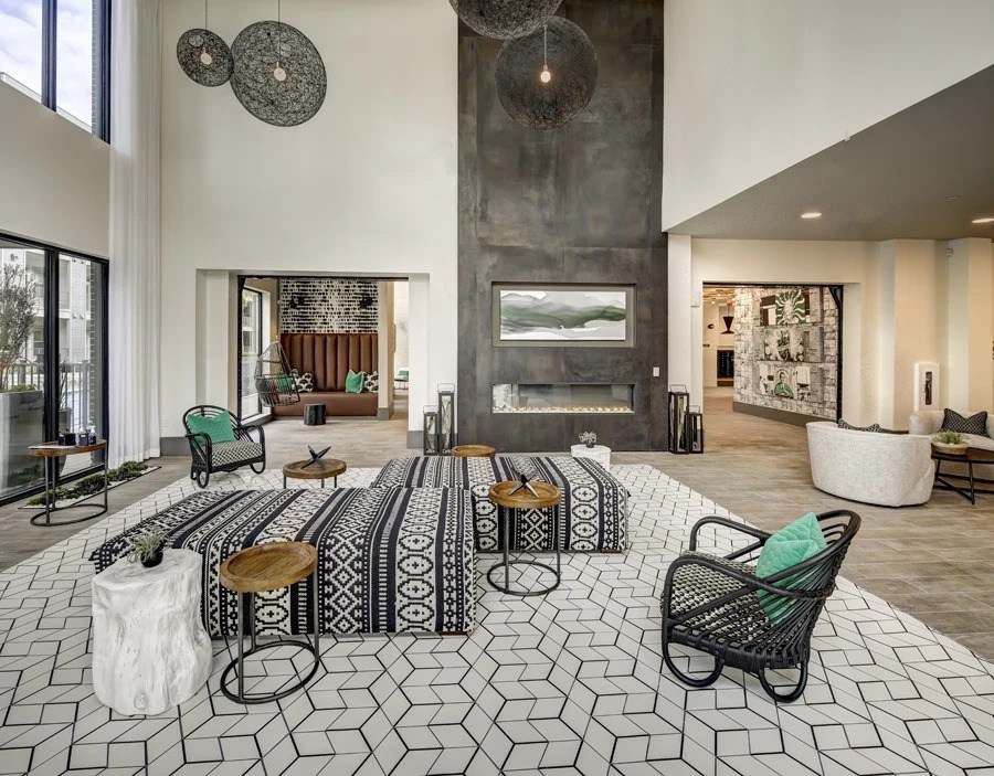 A black and white tiled floor with a patterned rug and a few chairs and tables at Arise Riverside Apartments, Texas 78741