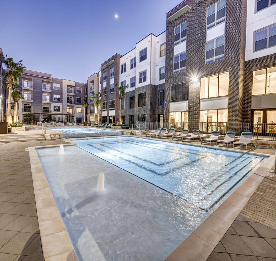 A large swimming pool in front of apartment buildings at dusk at Arise Riverside Apartments, Austin, TX