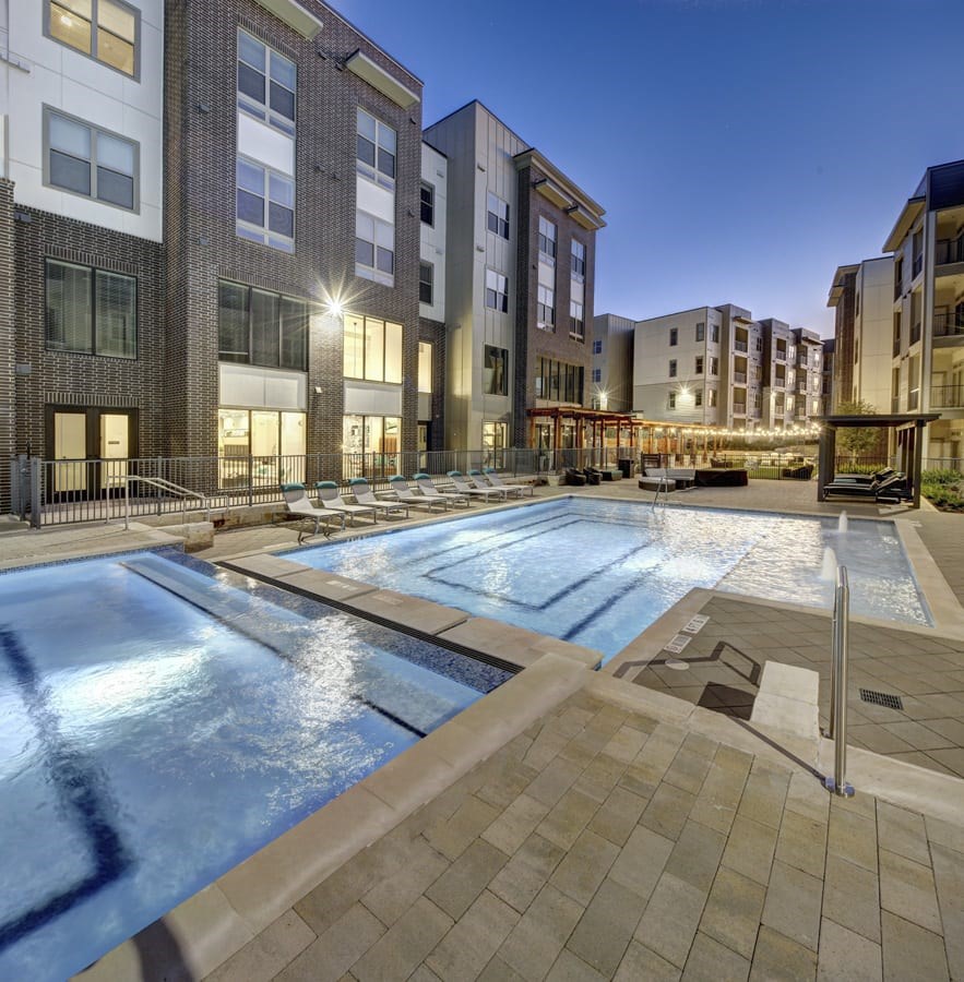 A swimming pool in front of apartment buildings at dusk at Arise Riverside Apartments, Austin