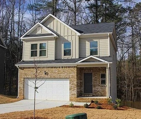 A two-story house with a garage and a stone wall.