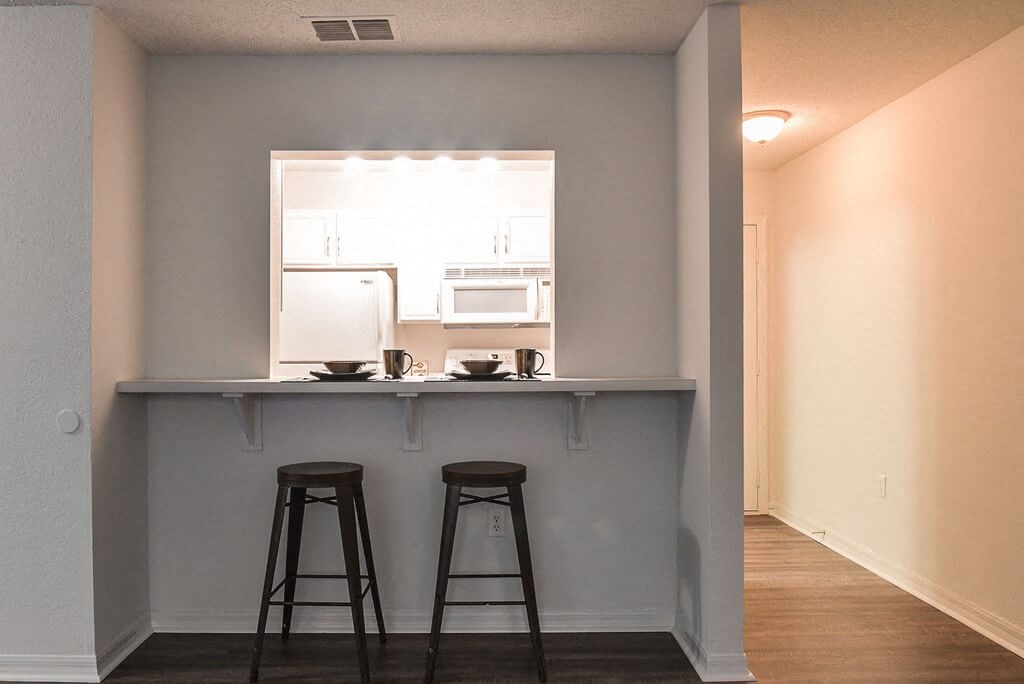a kitchen with two bar stools in front of a window