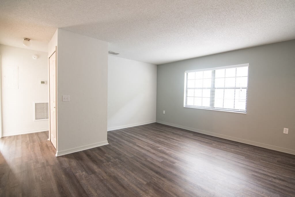 an empty living room with wood floors and a window