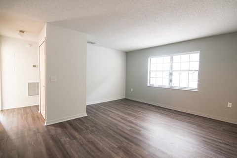 an empty living room with wood floors and a window