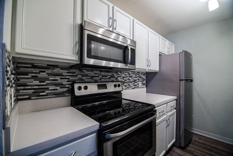 a kitchen with white cabinets and a stove and a microwave