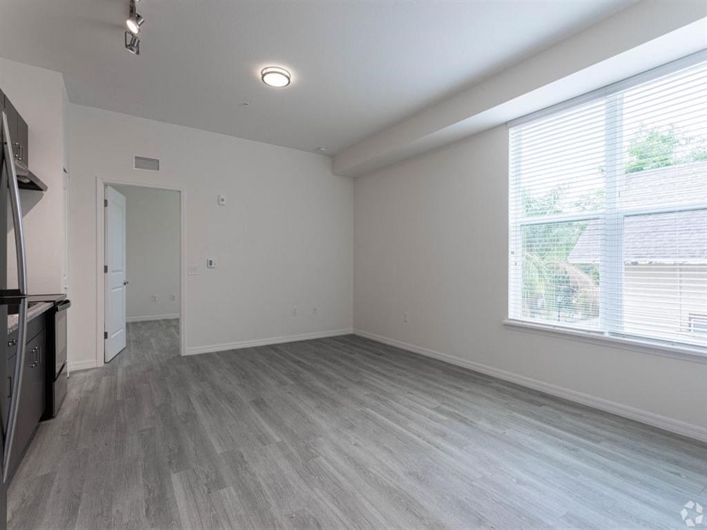 an empty living room with a large window and wood floors