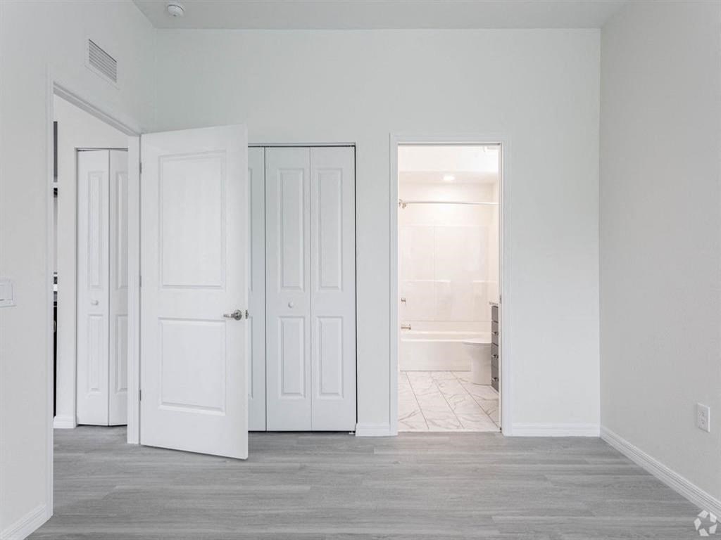 an empty room with white doors and a bathroom