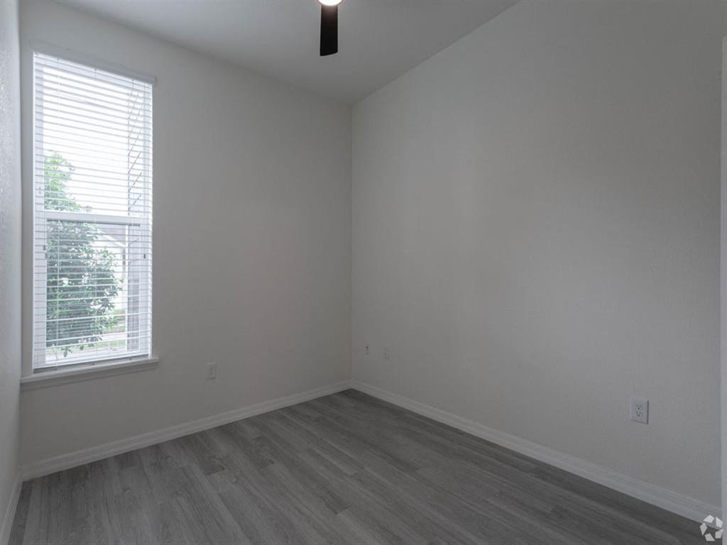 an empty room with a window and wooden floors