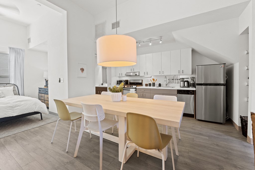 a dining room with a wooden table and chairs and a kitchen with stainless steel appliances