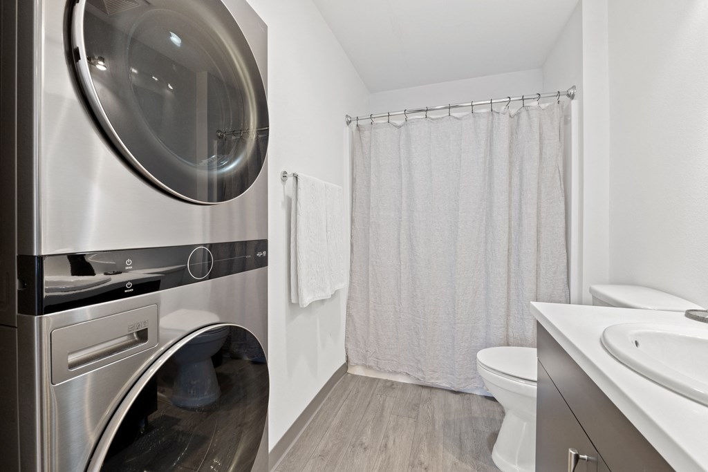 a washer and dryer in a bathroom with a shower and a toilet