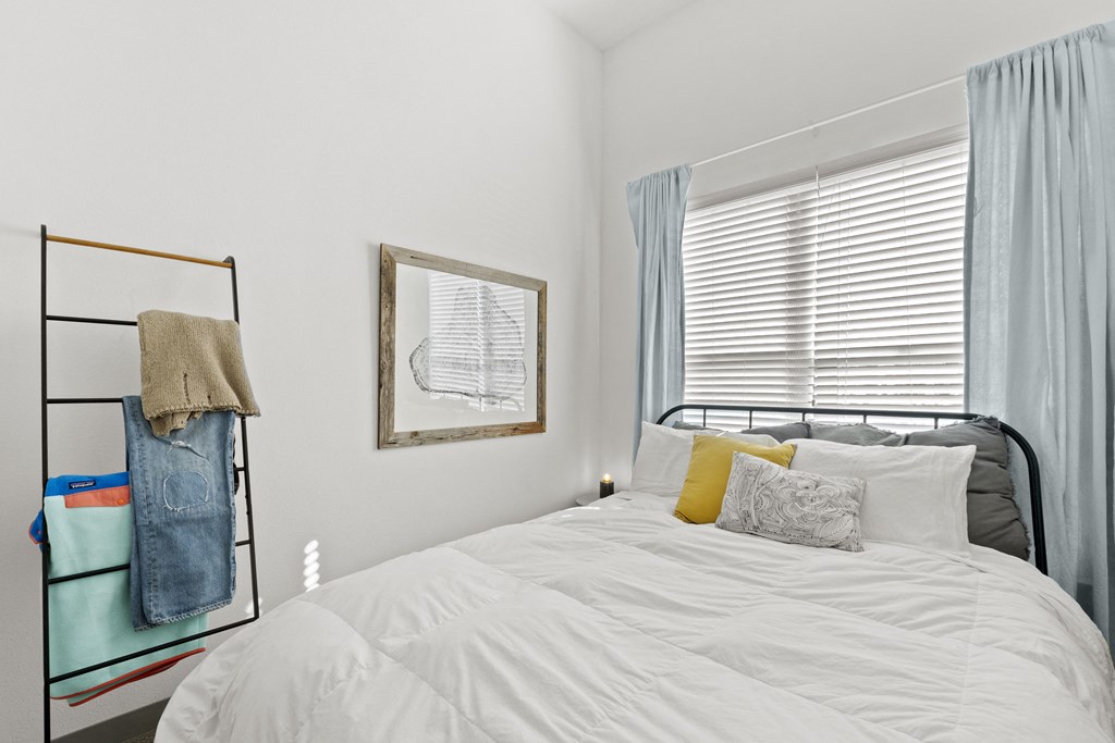 a white bedroom with a bed and a window