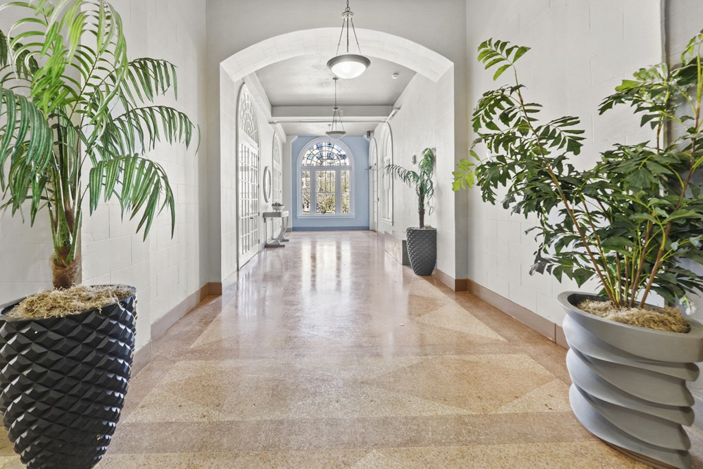 a hallway with potted plants and white walls and a blue door