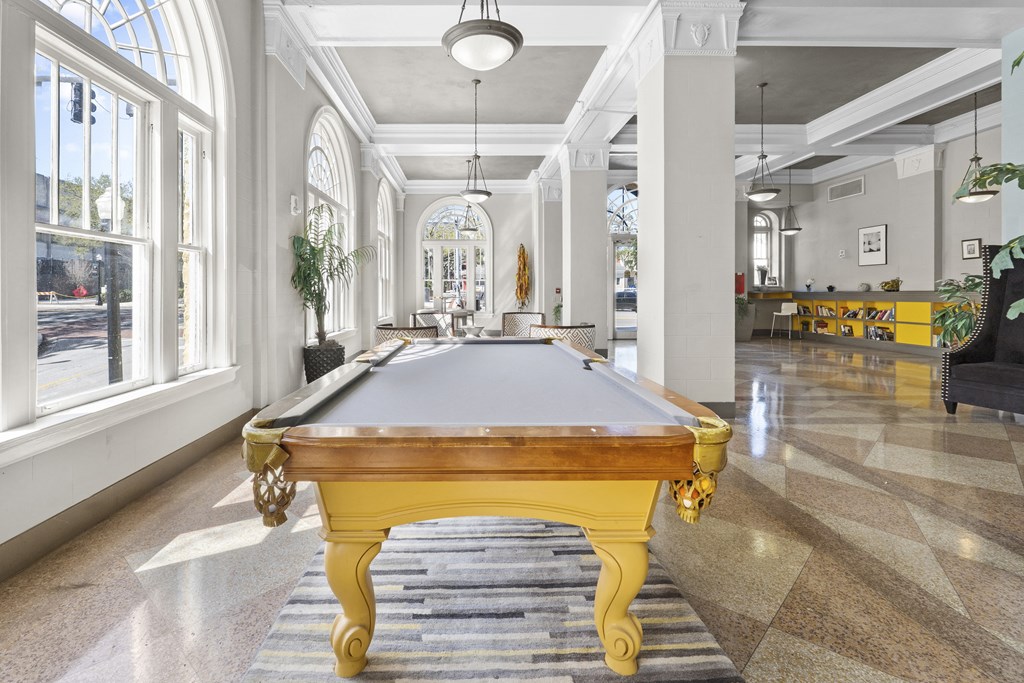 a pool table in the center of a room with large windows