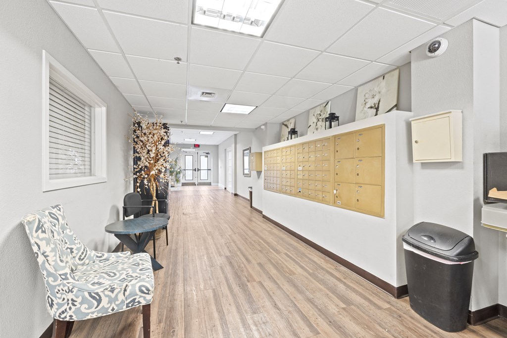 a long hallway with a chair and a table and a wall with a bulletin board