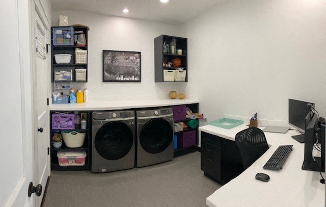 a room with a washing machine and a desk with a computer