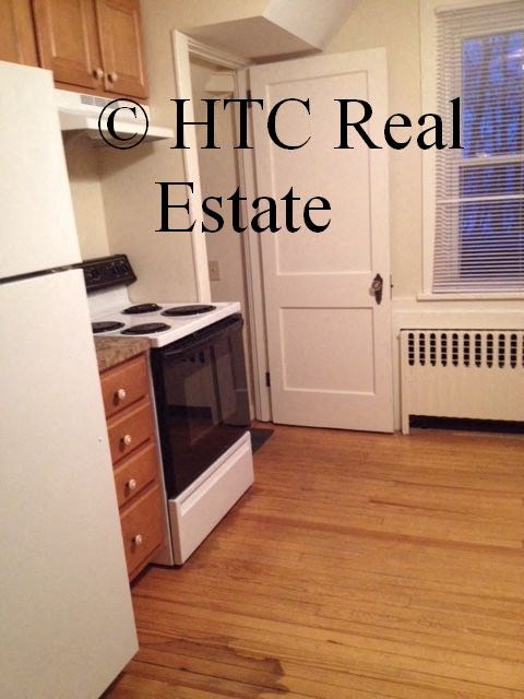 A kitchen with a white refrigerator and a white door.