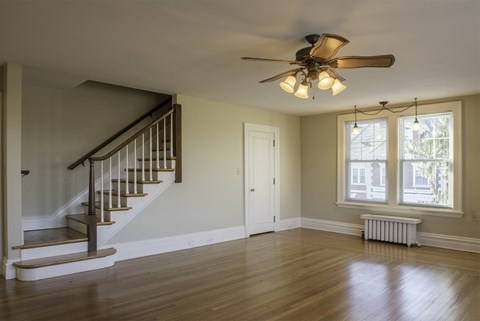 an empty living room with a staircase and a ceiling fan