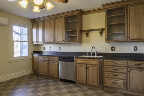 A kitchen with wooden cabinets and a checkered floor.