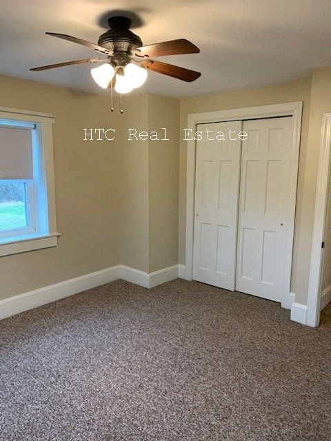 A room with a ceiling fan and carpeted floor.