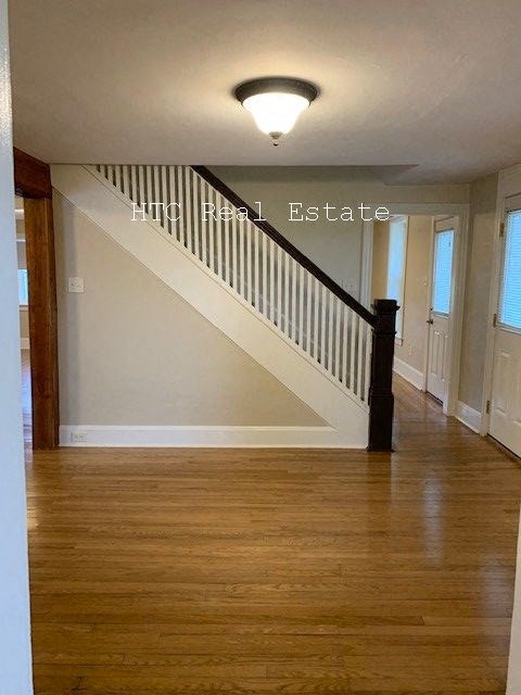 A wooden staircase with a black railing and a light on the ceiling.