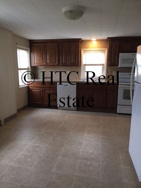 A kitchen with brown cabinets and a white refrigerator.