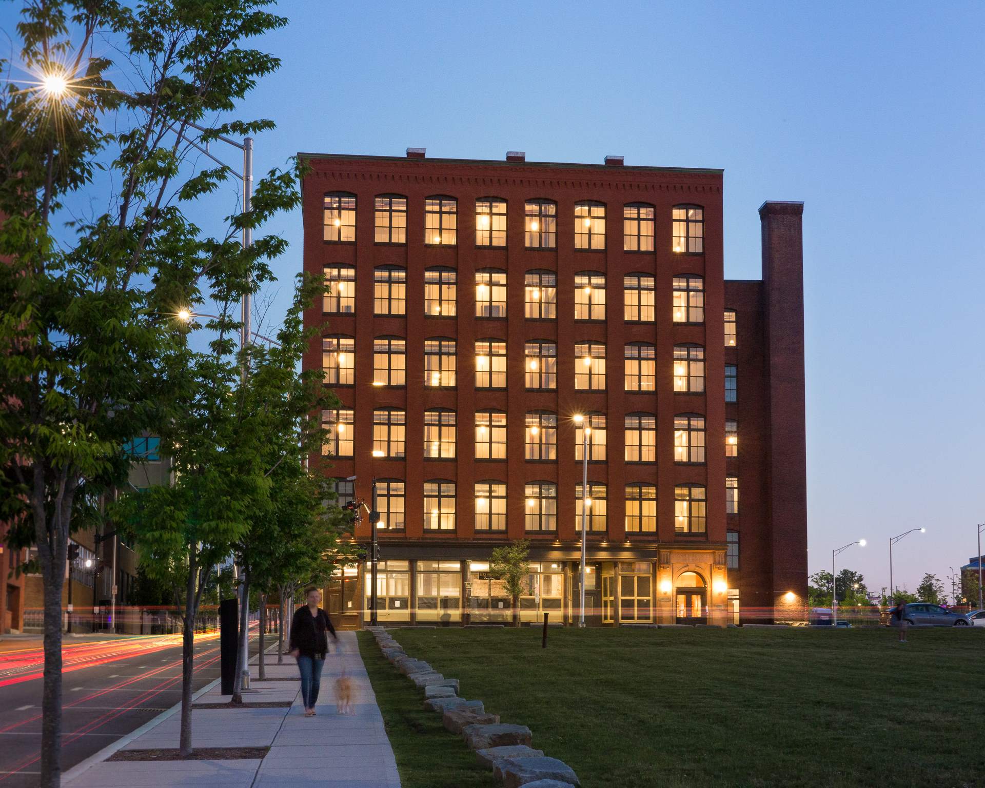 a man walks down a sidewalk in front of a tall building at night