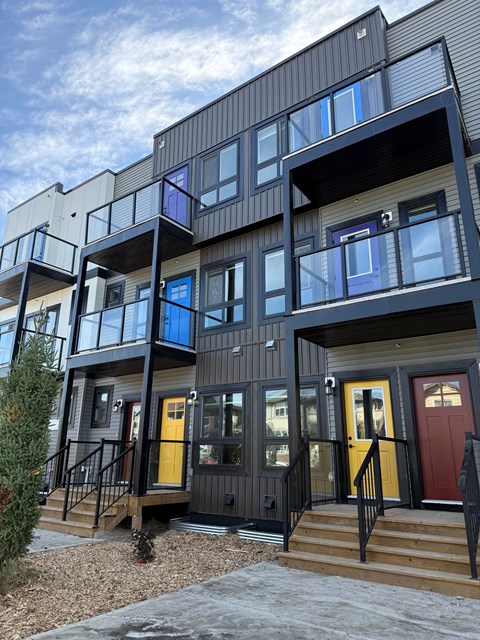 A modern building with balconies and doors in various colors.