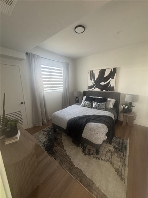 A bedroom with a bed, nightstand, and window.