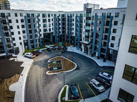 A parking lot in front of a building with cars parked.