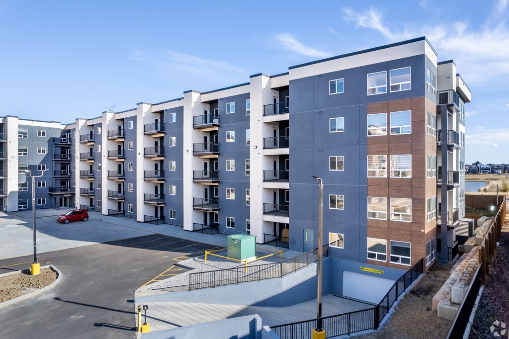 A row of modern apartment buildings with a red car parked in front.