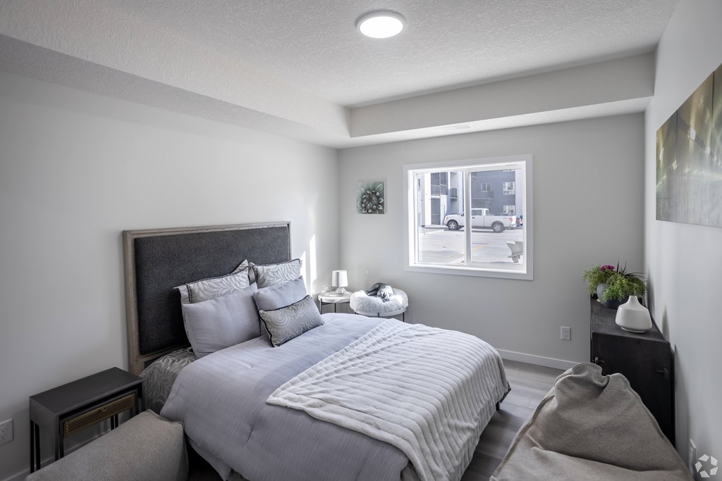 A bedroom with a large bed and a picture of a house on the wall.