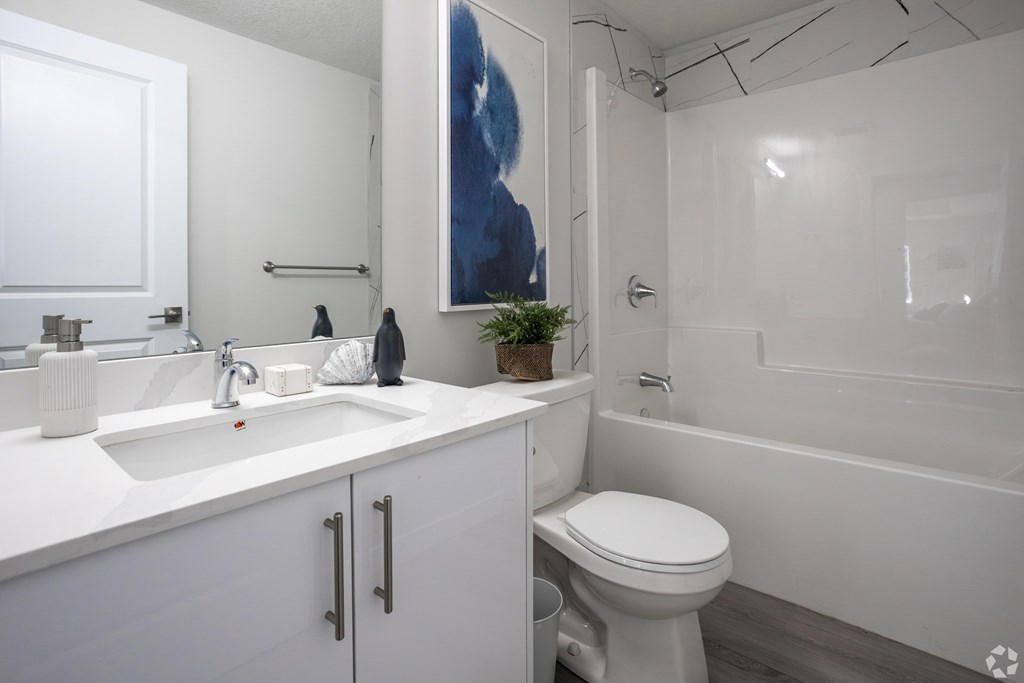 A white bathroom with a toilet, sink, and bathtub.