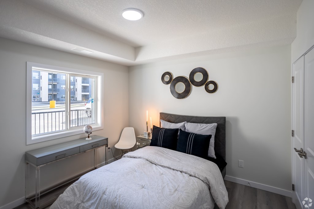 A bedroom with a bed, chair, and window.