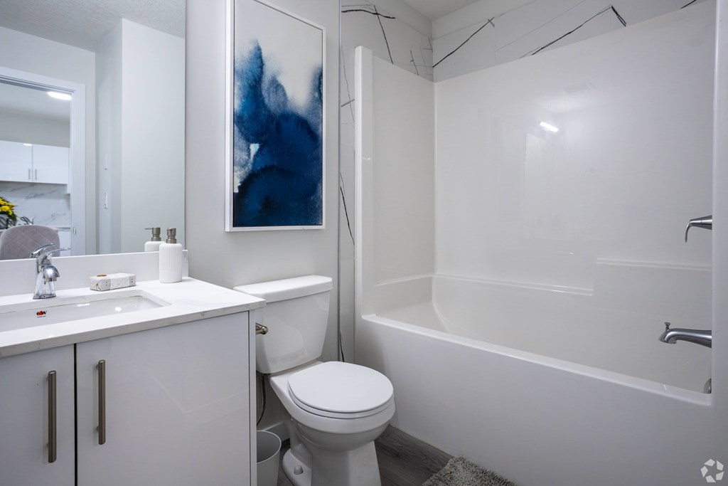 A white bathroom with a toilet, sink, and bathtub.
