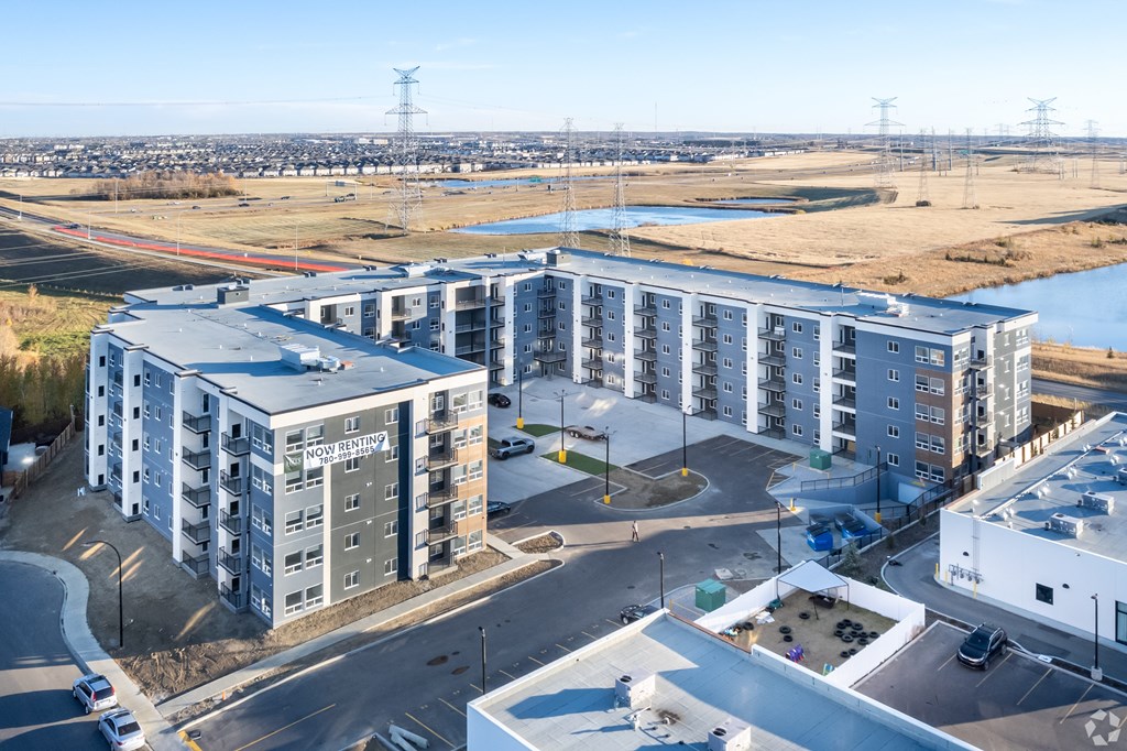 A modern apartment complex with a parking lot in front.