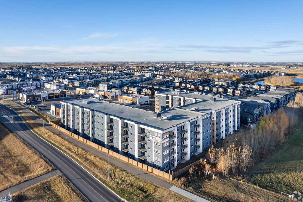 A large building complex is situated on a hill with a road running in front of it.