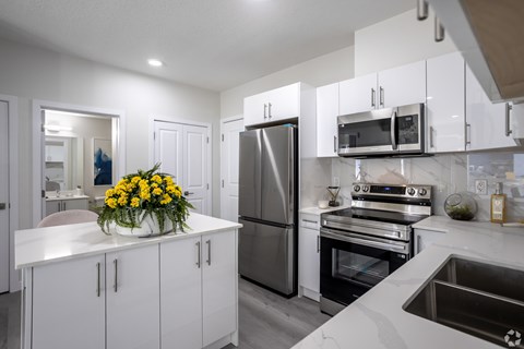 A modern kitchen with white cabinets and stainless steel appliances.at Hills on 36, Edmonton Alberta