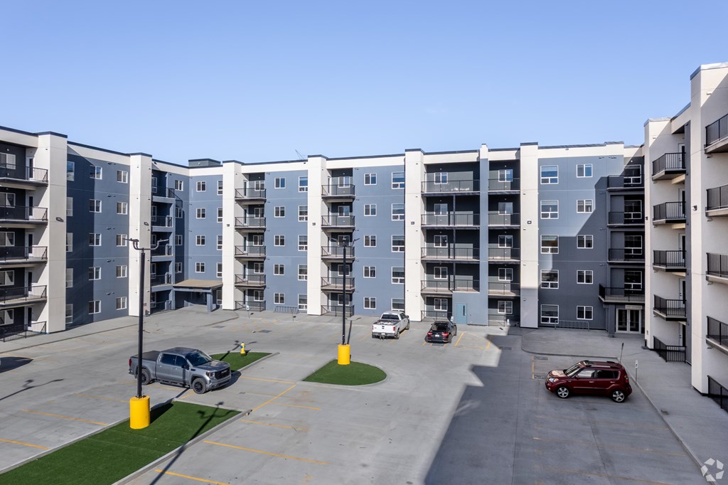 A parking lot in front of a large apartment complex.