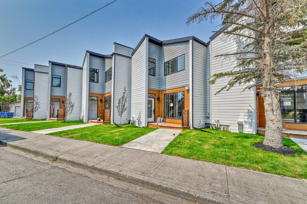 A row of modern houses with grey siding and wooden doors.