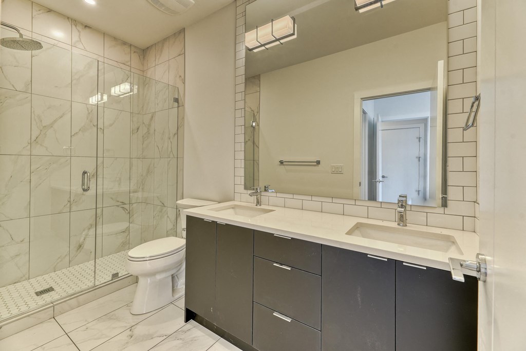 A bathroom with a toilet, sink, and mirror.
