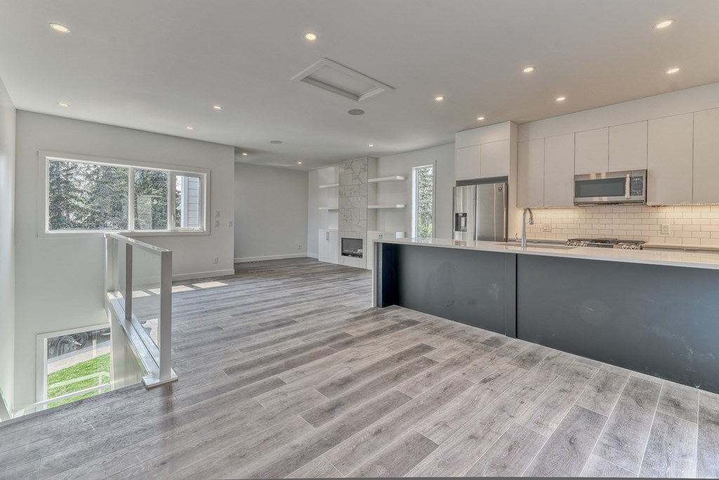 A modern kitchen with a wooden floor and white walls.