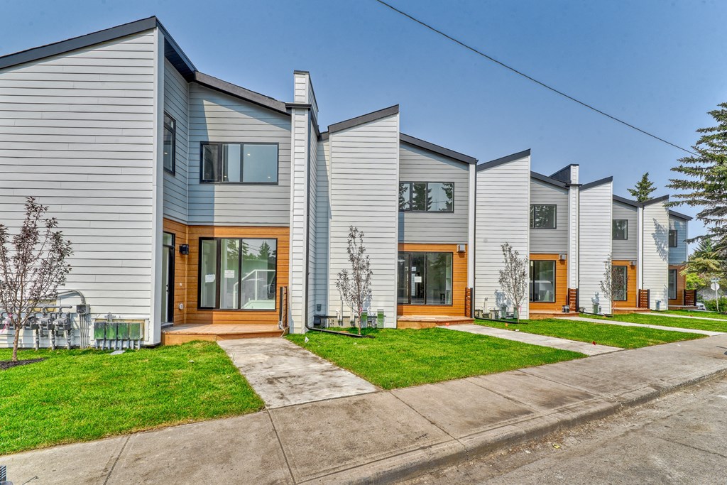 A row of modern houses with grey siding and wooden doors.