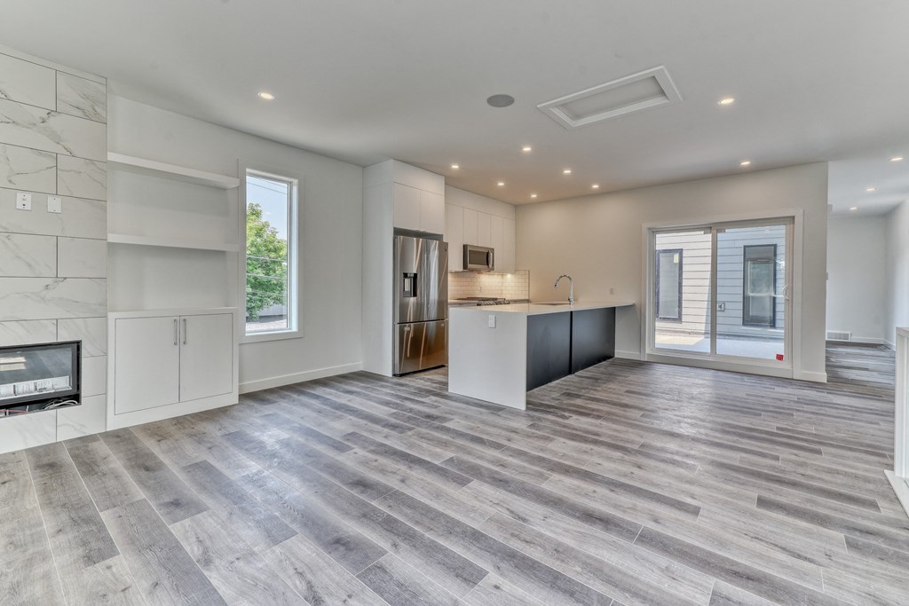 A spacious kitchen with a marble wall and a wooden floor.