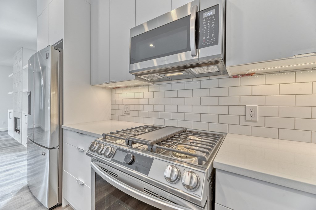 A modern kitchen with a stainless steel stove and microwave above it.