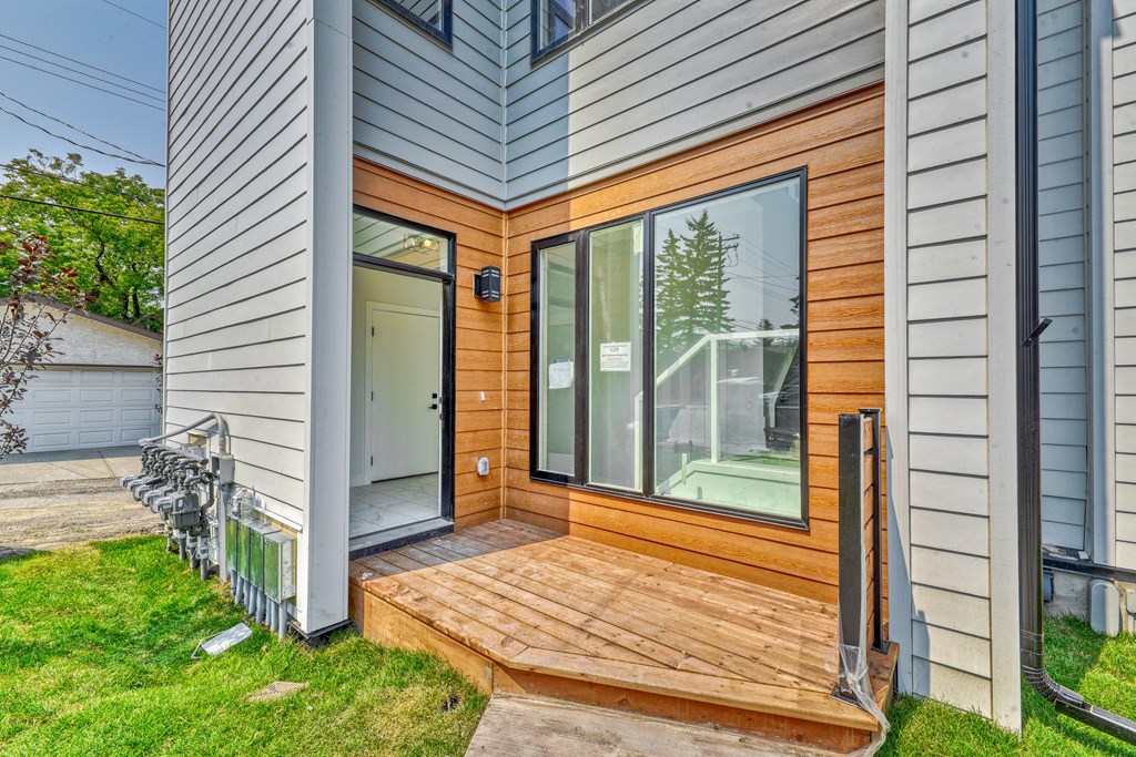 A modern house with a wooden deck and sliding glass doors.